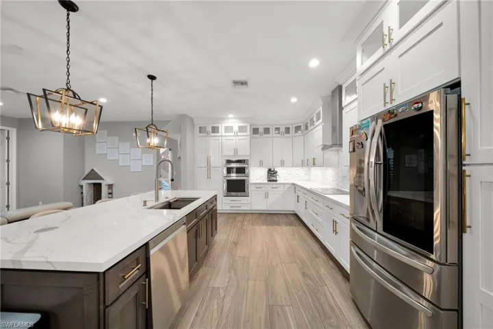 Kitchen featuring an island with sink, stainless steel appliances, an inviting chandelier, visible vents, and a sink