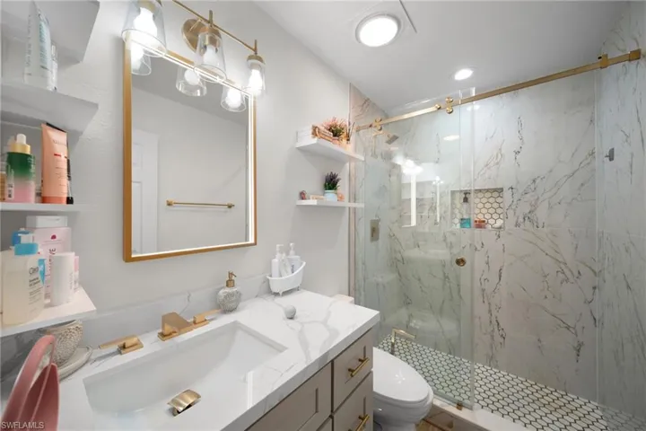Full bath featuring toilet, vanity, a marble finish shower, and recessed lighting
