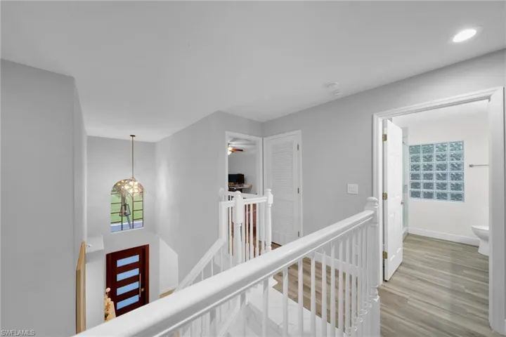 Hall featuring recessed lighting, wood finished floors, baseboards, and an upstairs landing