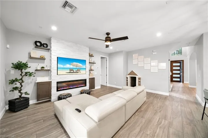 Living area featuring baseboards, light wood finished floors, a large fireplace, and visible vents