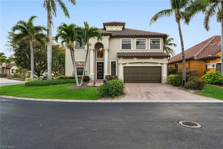 Mediterranean / spanish home with a front lawn, a tiled roof, an attached garage, stucco siding, and decorative driveway
