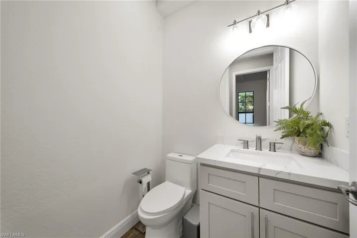 Bathroom with toilet, vanity, and wood finished floors