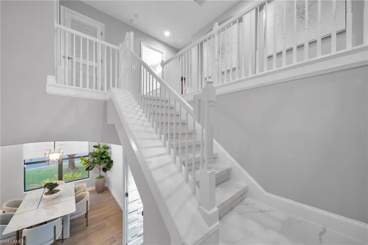 Staircase featuring a wealth of natural light, an inviting chandelier, and baseboards