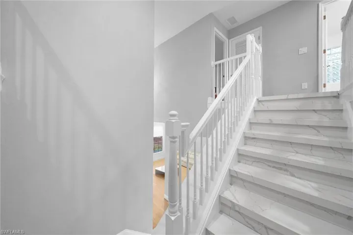Stairs with visible vents, marble finish floor, and a towering ceiling
