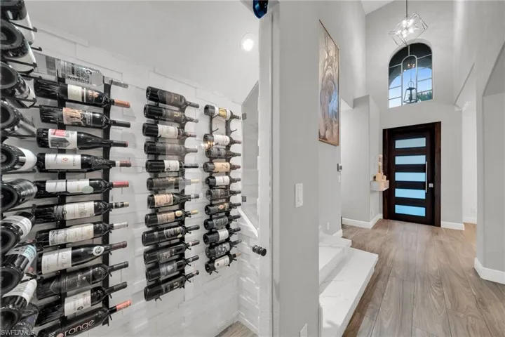 Wine room featuring baseboards, wood finished floors, and a high ceiling