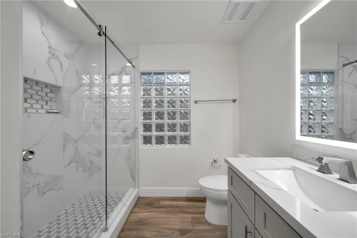 Bathroom featuring a marble finish shower, toilet, vanity, and visible vents