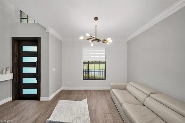 Entryway featuring wood finished floors, a wealth of natural light, ornamental molding, and a notable chandelier