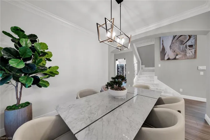 Dining room featuring baseboards, an inviting chandelier, wood finished floors, stairs, and ornamental molding
