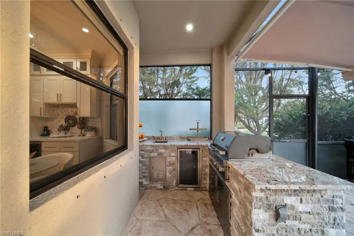Bathroom with recessed lighting, beverage cooler, a sink, stone finish flooring, and decorative backsplash