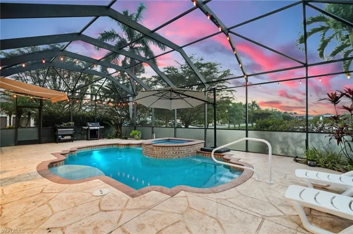 View of swimming pool featuring glass enclosure and a pool with connected hot tub