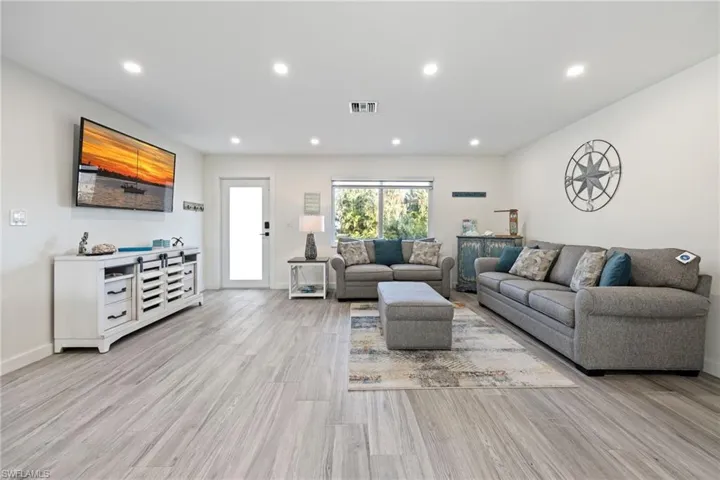 Living room with light wood-type flooring and recessed lighting