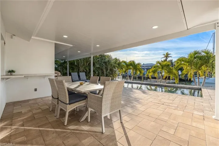 View of patio with outdoor dining area, an outdoor pool, and a water view