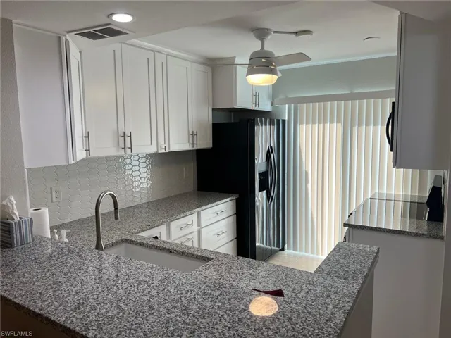 Kitchen featuring dark stone countertops, white cabinetry, decorative backsplash, black / electric stove, and ceiling fan