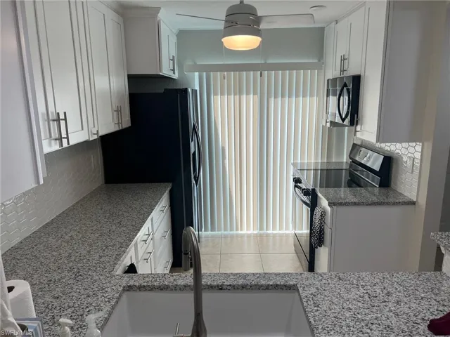 Kitchen featuring decorative backsplash, white cabinets, stainless steel range with electric cooktop, and light stone countertops
