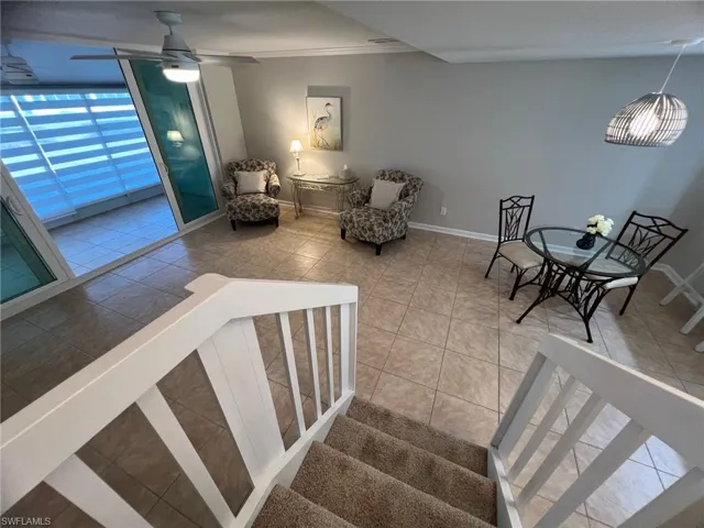 Staircase featuring tile patterned floors, ceiling fan, and crown molding