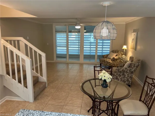 Living room with crown molding, light tile patterned floors, stairs, and a ceiling fan