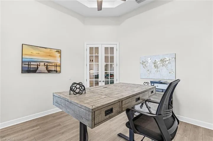 Tray ceiling, wood-finish flooring, accent wall with paneling, recessed lighting, and modern chandelier