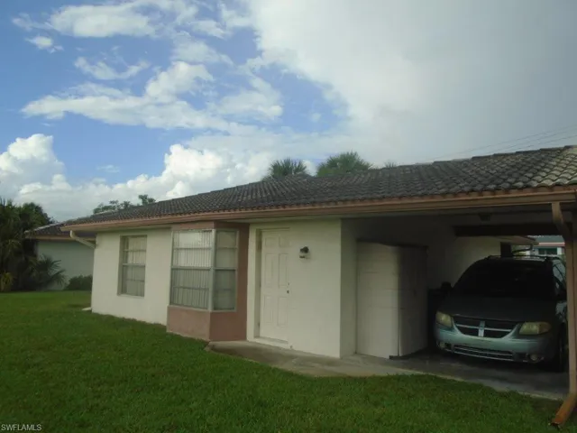 View of side of home with a carport and a lawn