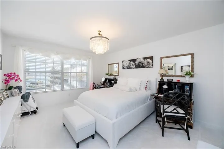 Bedroom with an inviting chandelier and light carpet