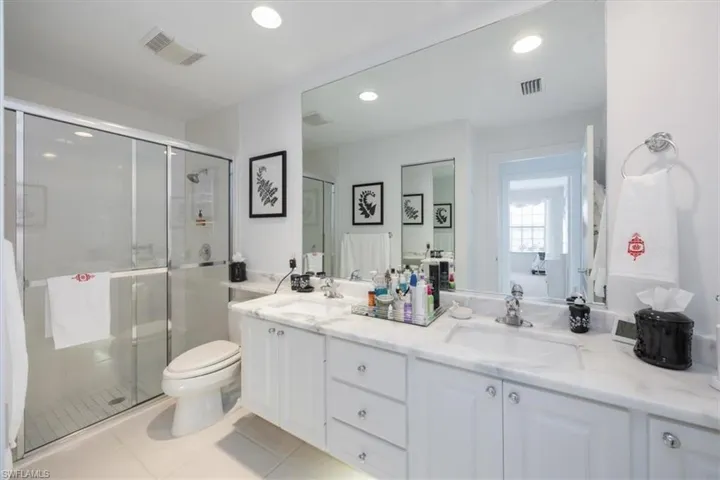 Bathroom with tile patterned floors, toilet, an enclosed shower, and vanity