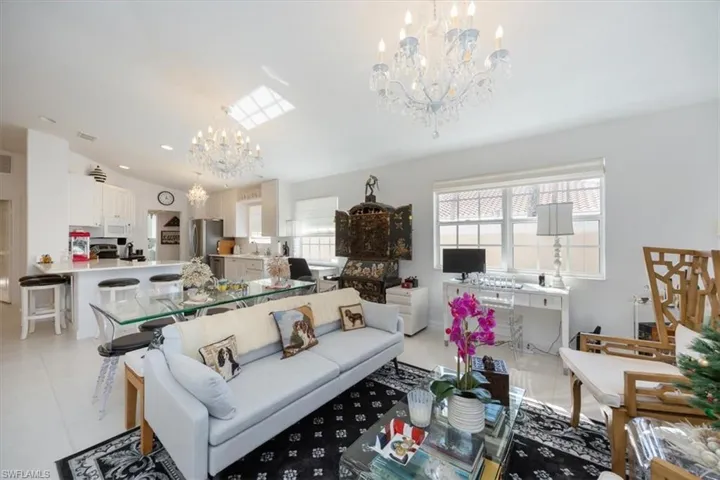 Tiled living room featuring lofted ceiling, sink, and a notable chandelier
