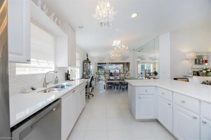 Kitchen featuring white cabinetry, dishwasher, pendant lighting, and a chandelier