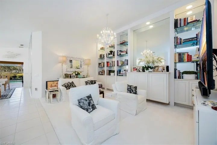 Sitting room with light tile patterned flooring, a chandelier, and built in shelves