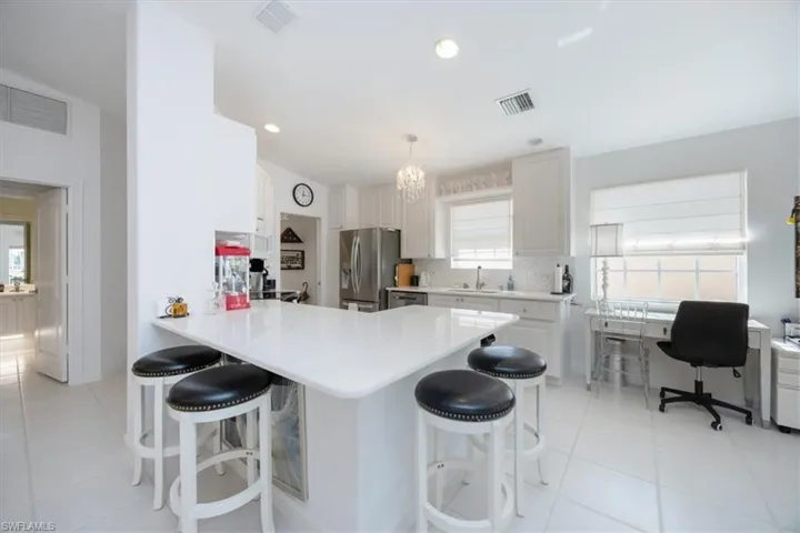 Kitchen with appliances with stainless steel finishes, white cabinetry, sink, a kitchen breakfast bar, and kitchen peninsula