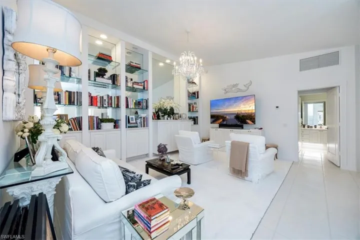 Living room featuring light tile patterned flooring, built in features, and a notable chandelier