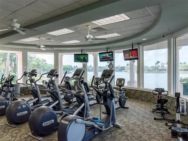 Gym featuring ceiling fan, a paneled ceiling, carpet, and a wealth of natural light
