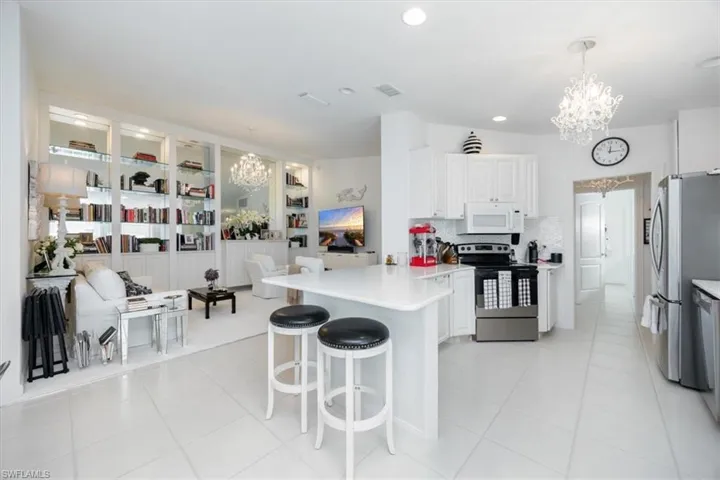 Kitchen with an inviting chandelier, decorative light fixtures, white cabinetry, and appliances with stainless steel finishes