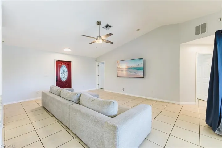 Living area featuring lofted ceiling, light tile patterned flooring, and ceiling fan