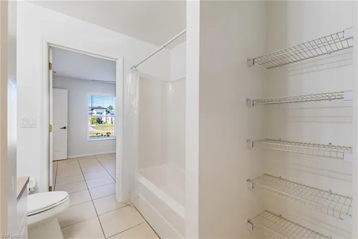 Bathroom featuring light tile patterned floors, shower / tub combo with curtain, and vanity