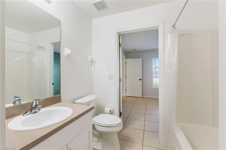 Bathroom featuring vanity, light tile patterned floors, and shower / bathtub combination with curtain