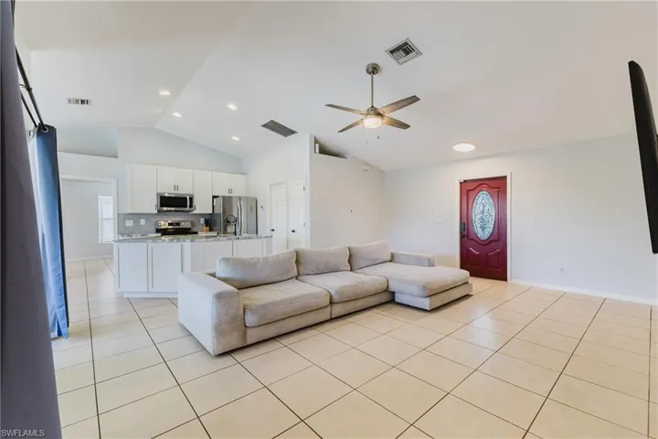 Living room featuring ceiling fan, light tile patterned floors, plenty of natural light, recessed lighting, and high vaulted ceiling