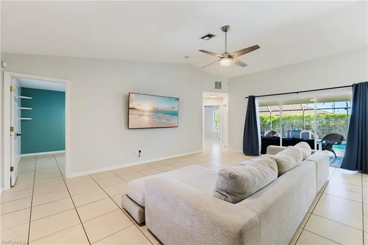 Living area with light tile patterned floors, lofted ceiling, and ceiling fan