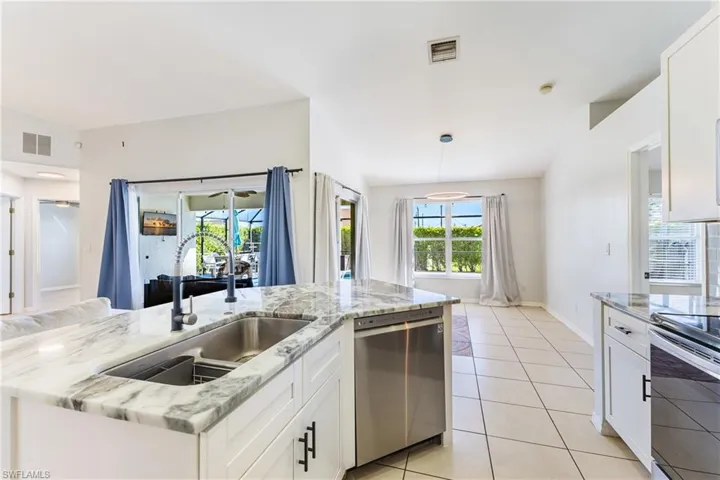 Kitchen featuring white cabinets, light stone countertops, stainless steel appliances, and healthy amount of natural light