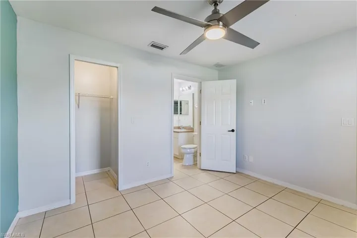 Unfurnished bedroom with a ceiling fan, a walk in closet, and light tile patterned floors