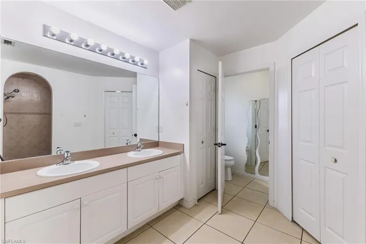 Full bath featuring a closet, double vanity, light tile patterned flooring, and a shower