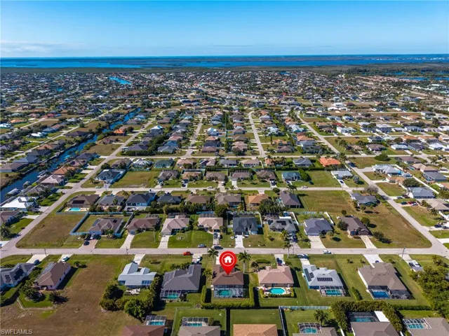 Aerial view of property and surrounding area featuring nearby suburban area and a large body of water