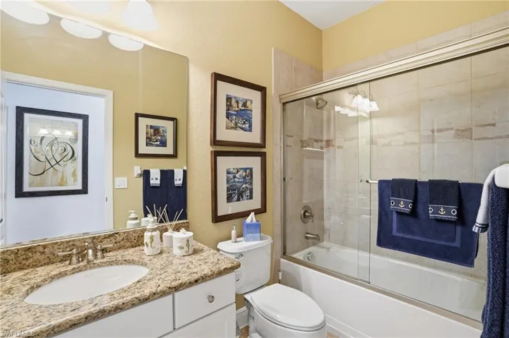 Full bath featuring bath / shower combo with glass door, vanity, and a textured wall