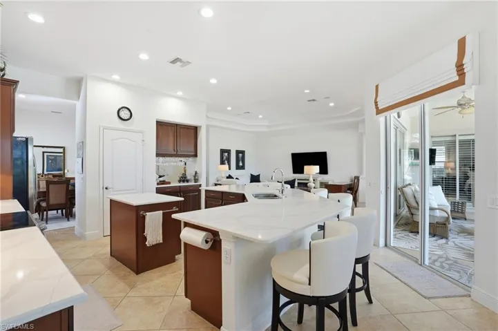 Kitchen with light stone countertops, a breakfast bar, recessed lighting, light tile patterned floors, and freestanding refrigerator