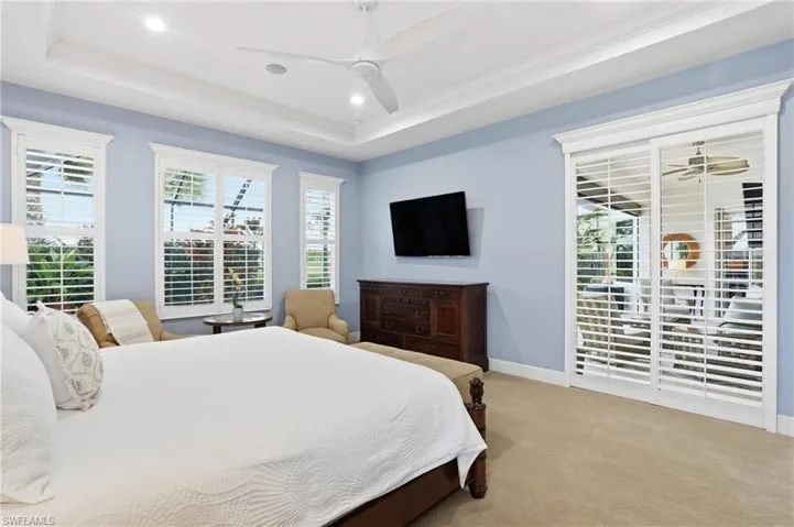 Bedroom with access to exterior, carpet floors, a ceiling fan, a tray ceiling, and ornamental molding