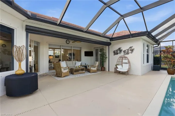 Rear view of house with a sunroom, a lanai, stucco siding, an outdoor hangout area, and a patio