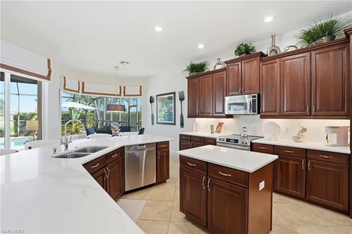 Kitchen featuring appliances with stainless steel finishes, backsplash, recessed lighting, decorative light fixtures, and light tile patterned flooring