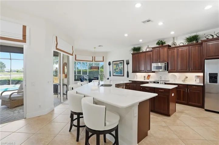 Kitchen with decorative backsplash, appliances with stainless steel finishes, a breakfast bar, light tile patterned floors, and recessed lighting