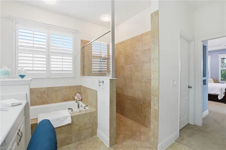 Full bathroom with connected bathroom, vanity, a bath, walk in shower, and light carpet