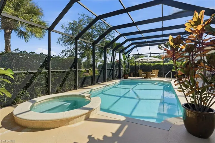 View of swimming pool featuring a pool with connected hot tub, a lanai, a sunroom, and a patio