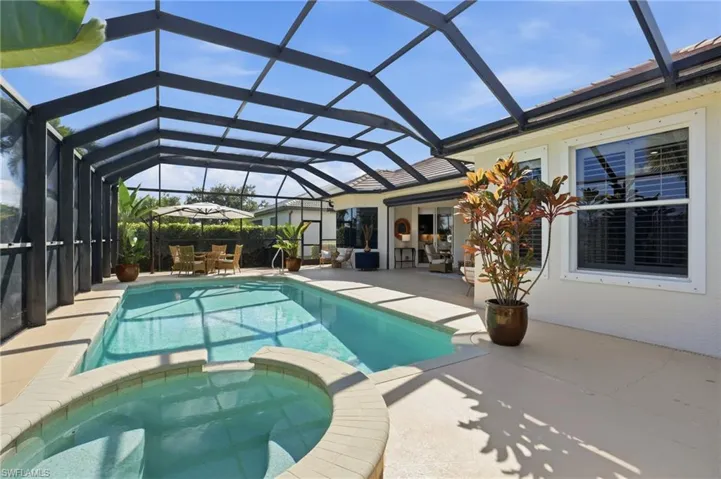 View of swimming pool featuring a sunroom, a pool with connected hot tub, a lanai, and a patio area