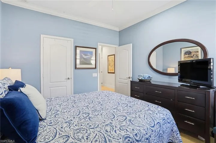 Bedroom featuring ornamental molding, light colored carpet, a ceiling fan, and a closet